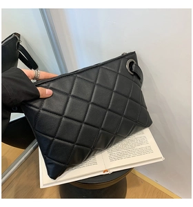 Macro detail of black quilted stitching and metallic ring on the elegant crossbody bag