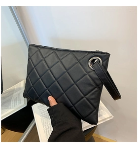 Detail of black quilted pattern leather clutch with silver metal eyelet and wrist strap