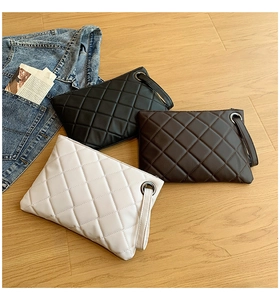 Flat lay of quilted crossbody bags in black, white, and brown on a light wood floor