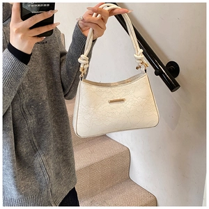 Detailed shot of white lace textured baguette bag with unique rope knot handle detail