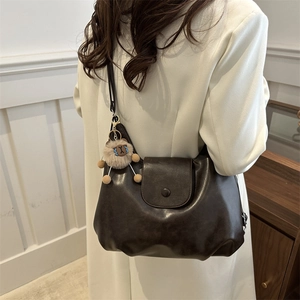 Retro large brown leather tote bag with a cute plush bear pendant shown on white coat