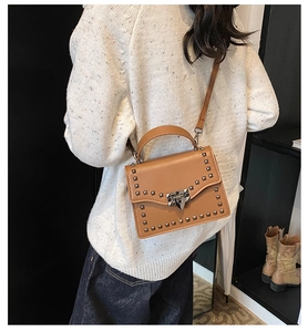 Rear view of model holding a brown crossbody bag with silver studs and matte PU finish