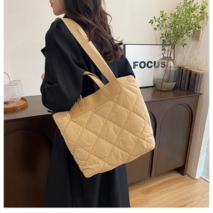 Vue détaillée d'un sac cabas matelassé beige avec large bandoulière porté par un mannequin