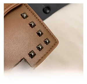 Detail of brown leather bag featuring square metallic rivets and precision stitching