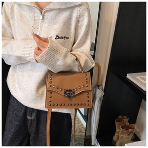 Detail of brown leather shoulder bag with square metal rivets and vintage clasp closure