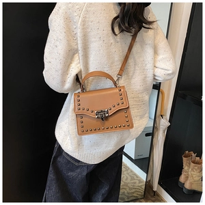 Detail of a brown leather crossbody bag with silver square studs and metal clasp lock