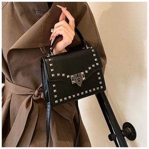 Detailed shot of black matte leather bag featuring silver square rivets and metal clasp