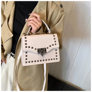 Close-up of white crossbody bag with dark grey metal rivets and a stylish push-lock