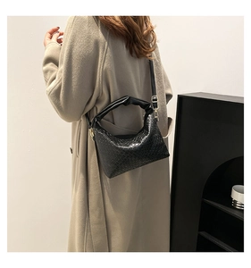 Detailed view of black crescent bag with woven texture and gold-tone adjustable strap
