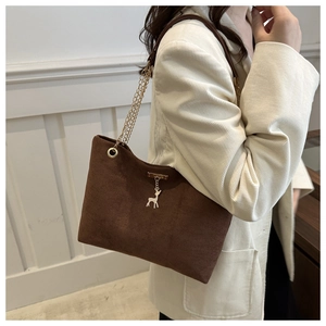 Détail d'un sac fourre-tout en daim marron avec bandoulière dorée et pendentif cerf