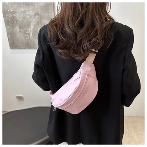 Close-up of light pink nylon crescent bag with adjustable strap worn as a crossbody