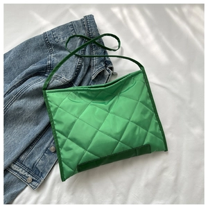 Detail of lime green quilted nylon crossbody tote with puffer texture and slim strap