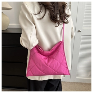 Detailed view of pink quilted shoulder bag featuring large rhombus stitching on model
