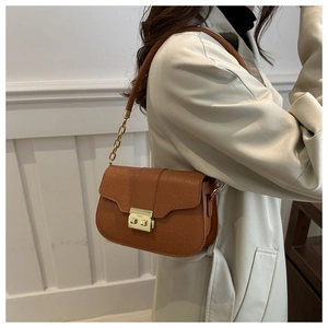 Detail of brown crocodile pattern shoulder bag with metal buckle and chain strap