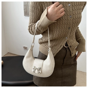 Vue détaillée du sac demi-lune plissé crème avec un nœud décoratif en métal argenté