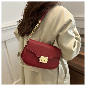 Close-up of red crocodile pattern shoulder bag with gold chain strap on beige trench coat