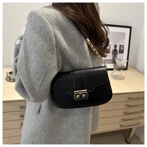 Detail view of black crocodile pattern faux leather handbag with gold metal clasp lock