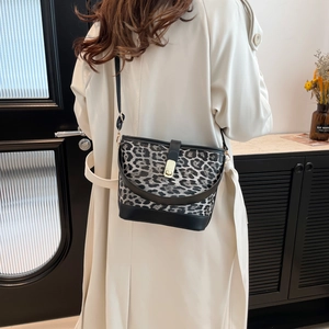 Leopard-Beuteltasche mit schwarzem Lederriemen getragen von Modell im beigen Trenchcoat