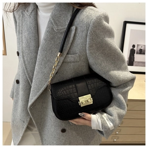 Detailed view of black crocodile pattern leather shoulder bag with golden metal buckle