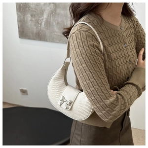 Détail du sac croissant plissé blanc avec nœud en métal argenté sur rabat en cuir verni