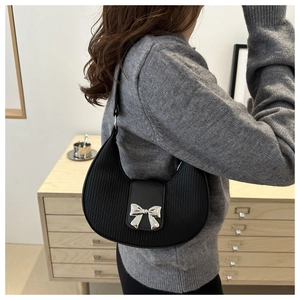 Détail du sac hobo plissé noir avec boucle nœud argenté porté par un mannequin