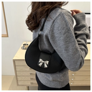 Détail du sac hobo noir avec texture plissée et nœud en métal argenté sur un modèle