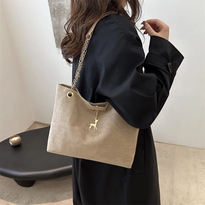 Grand sac cabas beige en daim avec chaîne dorée et breloque cerf sur mannequin