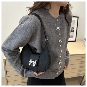 Detail of a black crescent shoulder bag with pleated texture and silver metal bow buckle