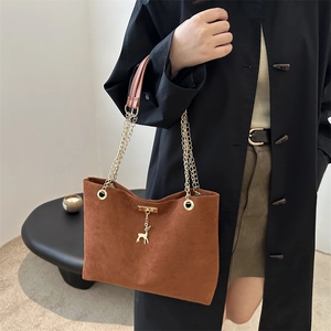 Sac cabas en daim marron avec pendentif cerf doré et bandoulière chaîne sur modèle