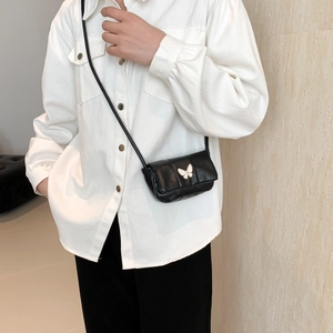 Chic quilted black mini crossbody bag with white butterfly charm on a female model