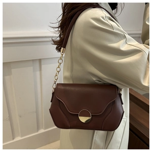 Detail of vintage brown leather bag with a gold crescent buckle and chain shoulder strap