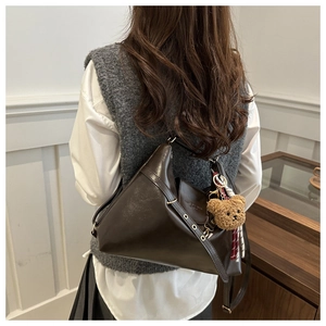 Détail du sac bandoulière vintage marron foncé en simili cuir avec un ours en peluche