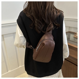 Close-up of a dark brown PU leather crossbody bag with silver zipper and nylon strap