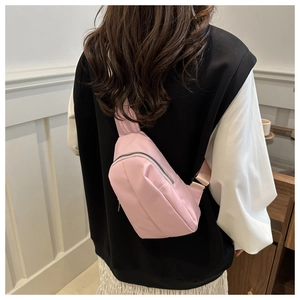 Detail of light pink crescent chest bag shown as a crossbody on model back view