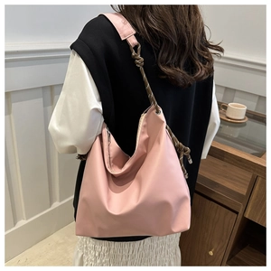 Pink hobo shoulder bag with woven rope strap shown on model in a minimalist room