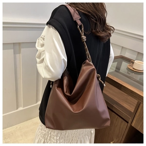 Detail of soft dark brown leather tote bag with unique knotted shoulder strap design