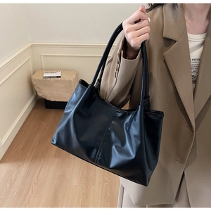 Detail of black soft leather tote bag with vertical stitching and dual handles