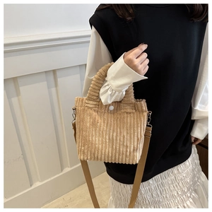 Detail view of beige corduroy handbag texture with wide stripes and round buckle fastener