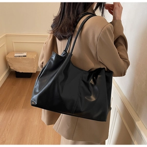 Detailed side view of a large black pleated tote bag worn on shoulder for commute
