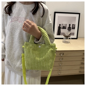 Detail of lime green corduroy handbag featuring round button closure and textured fabric