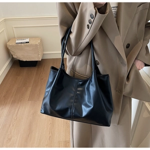 Detailed close-up of a black faux leather tote bag with elegant vertical stitching details