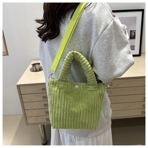 Close-up of light green corduroy bucket bag showing texture and white snap button closure