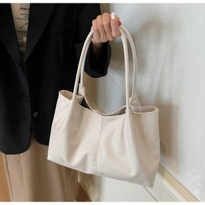 Detail of cream white pleated tote bag showing matte faux leather texture and soft folds