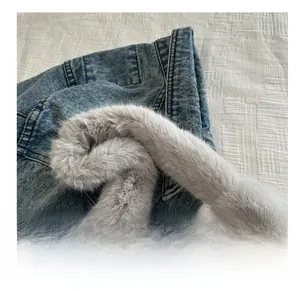 Dettaglio della tracolla in peluche grigia con fibbia in metallo argento su denim