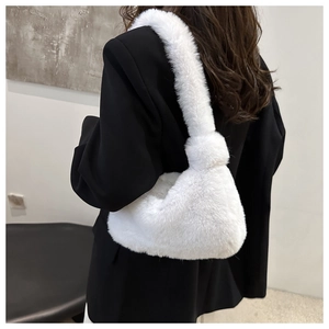 Dettaglio borsa tote in ecopelliccia crema con tracolla annodata su blazer nero