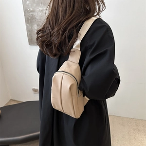 Minimalist beige PU leather chest bag with decorative pleats and wide strap on model