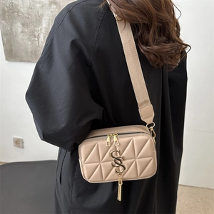 Beige quilted crossbody bag with golden SS logo and wide fabric strap on model