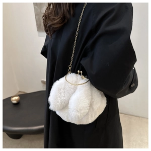 Gros plan du mini sac en peluche blanche avec cadre doré et bandoulière porté par un mannequin