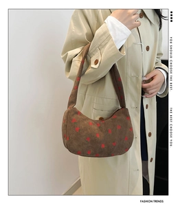 Détail du motif fraise sur sac bandoulière en velours côtelé marron avec un trench-coat