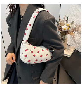 Sac croissant en velours côtelé blanc avec imprimé fraises porté par un mannequin